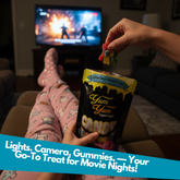 Person holding Yum Yum gummy bears with a TV in the background